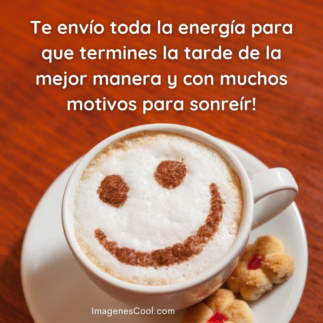 Una taza de café con espuma decorada con una cara sonriente, acompañada de galletas. Mensaje de energía y sonrisa
