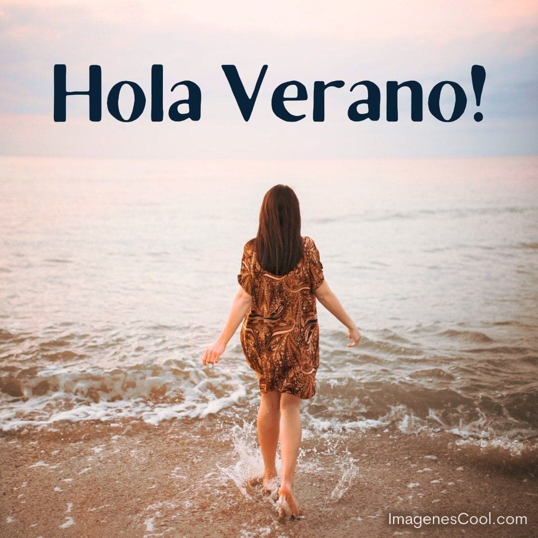 Mujer de espaldas camina en la playa con las letras 'Hola Verano' arriba
